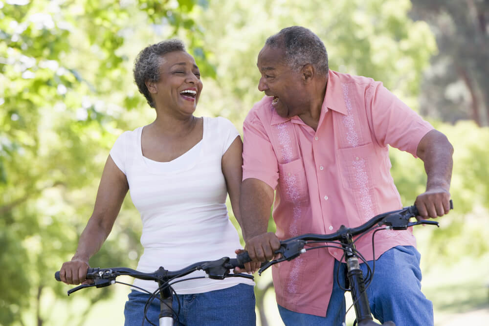 Older couple outside smiling and riding bikes